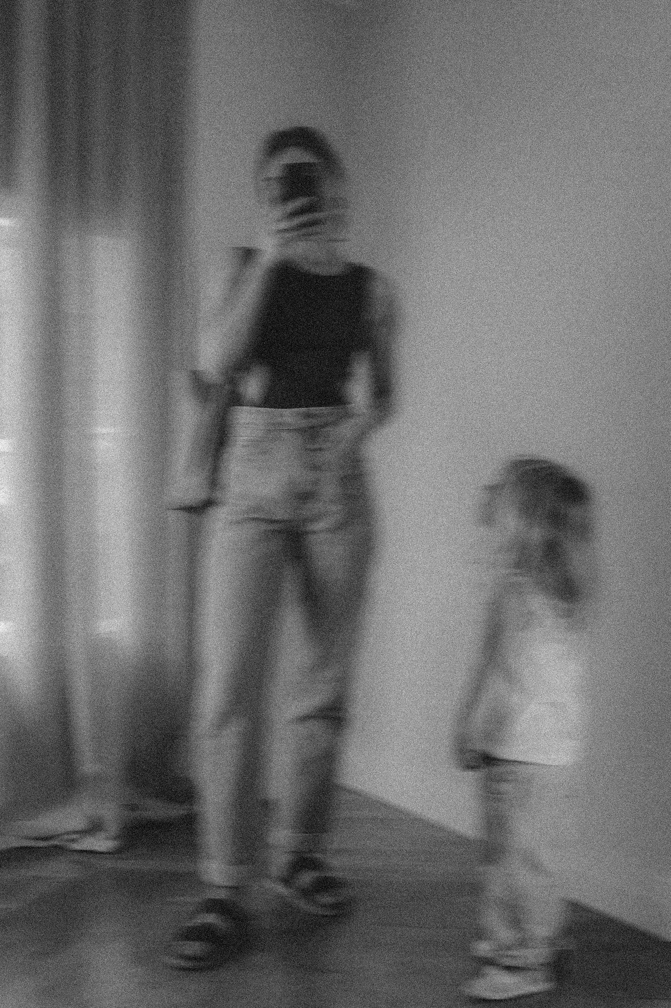 Soft, grainy black-and-white motion study of two figures in natural light
